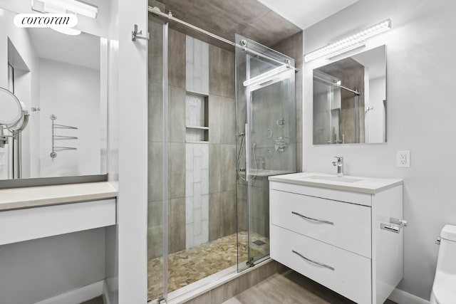 bathroom with toilet, vanity, and a shower with shower door