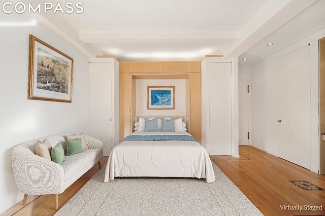 bedroom featuring hardwood / wood-style flooring and beam ceiling