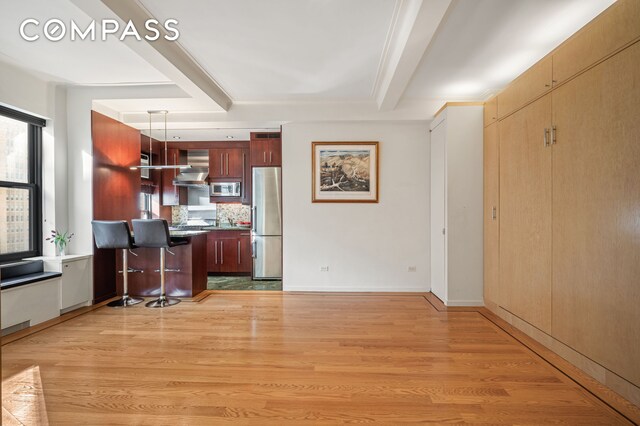 kitchen with decorative light fixtures, backsplash, light hardwood / wood-style floors, a breakfast bar area, and stainless steel appliances