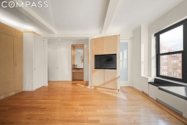 unfurnished living room featuring beamed ceiling, crown molding, and light hardwood / wood-style flooring