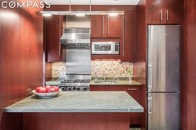 kitchen with stainless steel appliances, decorative backsplash, range hood, light stone counters, and sink