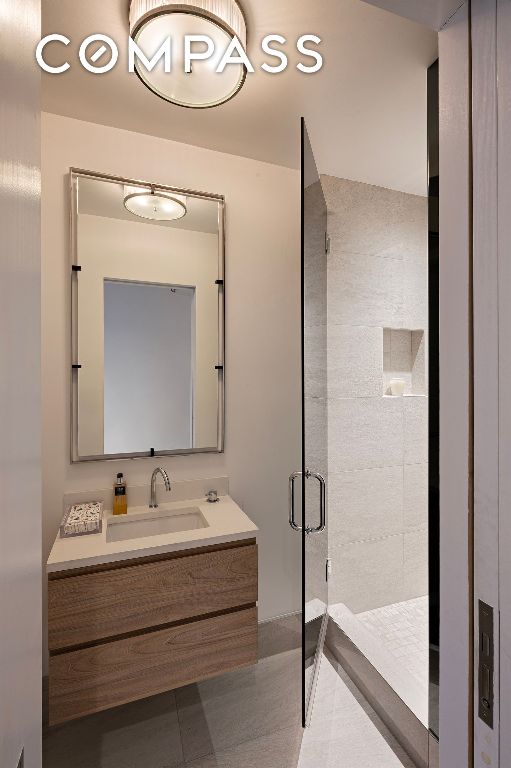 full bath with a stall shower, tile patterned flooring, and vanity