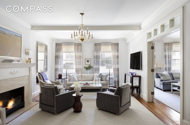 living area featuring baseboards, ornamental molding, wood finished floors, an inviting chandelier, and a high end fireplace