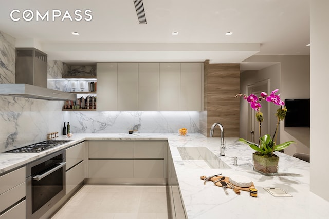 kitchen featuring island range hood, stainless steel appliances, a sink, light stone countertops, and modern cabinets