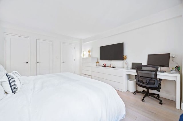 bedroom featuring multiple closets and light hardwood / wood-style flooring