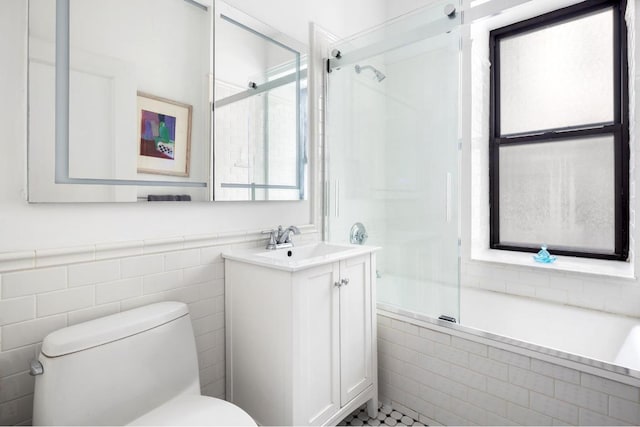 full bathroom featuring a wealth of natural light, combined bath / shower with glass door, vanity, and toilet