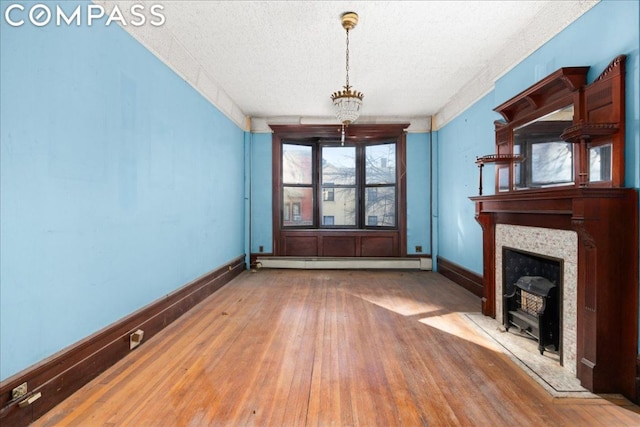 unfurnished living room with baseboard heating, a textured ceiling, a chandelier, and hardwood / wood-style floors