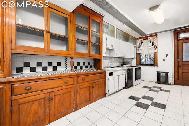 kitchen with tasteful backsplash, gas range gas stove, sink, white cabinetry, and radiator heating unit