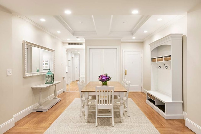 dining area with light hardwood / wood-style floors, crown molding, and coffered ceiling