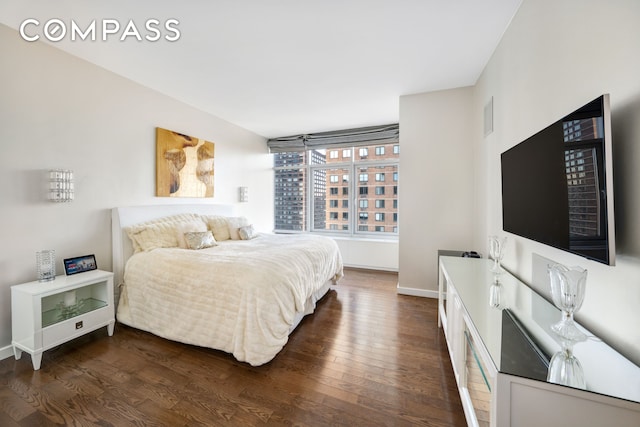 bedroom with dark wood-style floors and baseboards