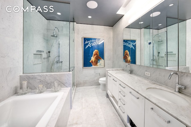 bathroom featuring tile walls, a stall shower, toilet, double vanity, and a garden tub