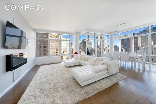 living room featuring dark wood-style floors, a city view, baseboards, and a wall of windows