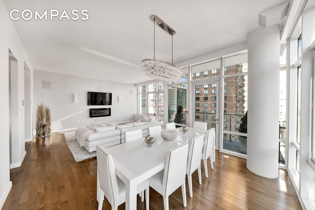 dining area featuring a chandelier, dark wood finished floors, and baseboards