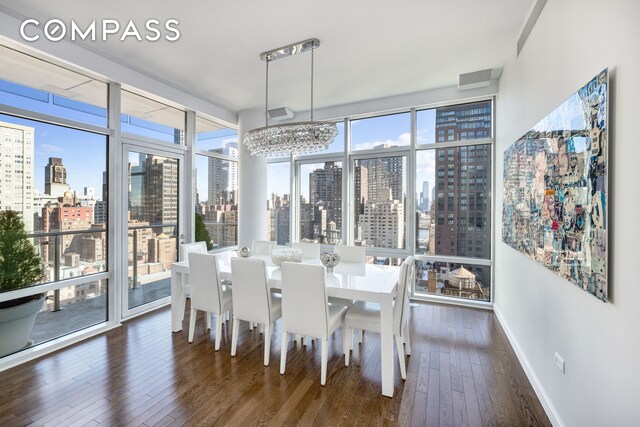 dining room featuring a view of city, visible vents, dark wood-type flooring, a chandelier, and baseboards