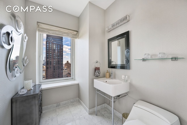 bathroom with baseboards, toilet, and marble look tile flooring