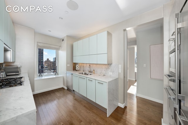 kitchen with a toaster, stainless steel appliances, dark wood-type flooring, a sink, and backsplash