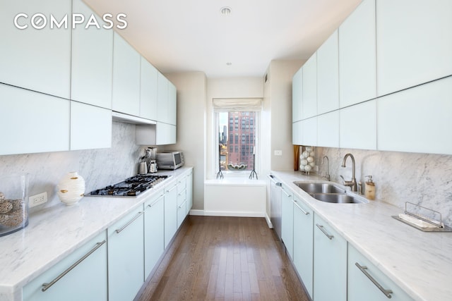 kitchen with dark wood-style flooring, a sink, backsplash, and gas stovetop