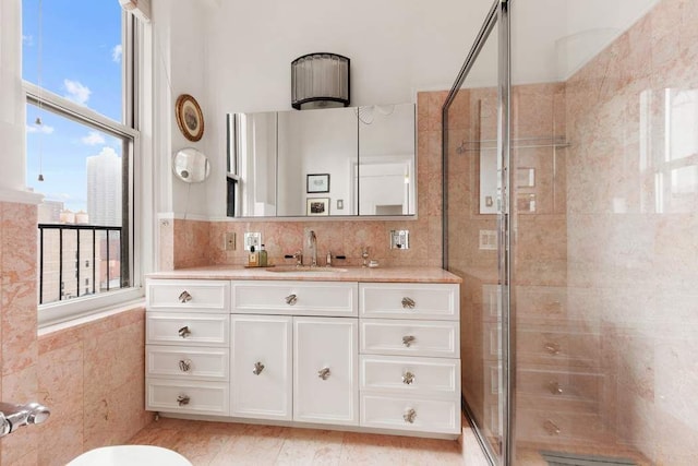 bathroom featuring a stall shower, vanity, and tile walls