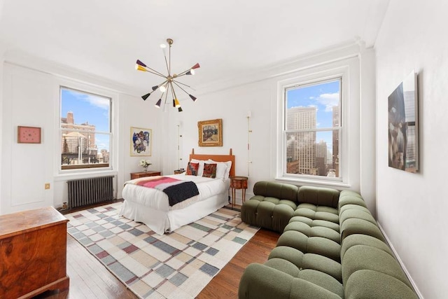 bedroom featuring light wood-type flooring, multiple windows, radiator, and a chandelier