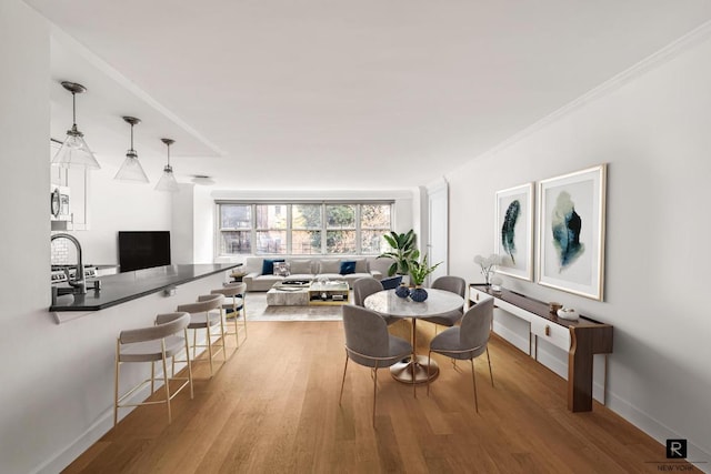 dining space featuring wood-type flooring and crown molding