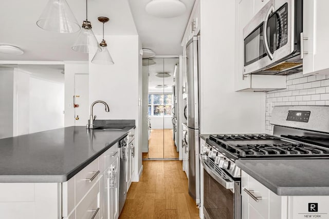 kitchen featuring decorative light fixtures, sink, light hardwood / wood-style flooring, stainless steel appliances, and white cabinets