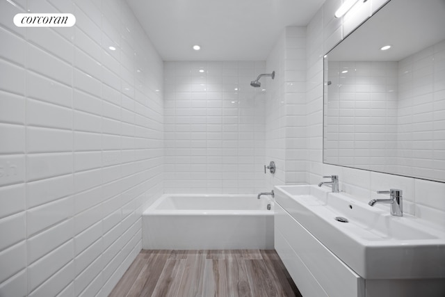 bathroom with tile walls, tiled shower / bath, hardwood / wood-style flooring, and vanity