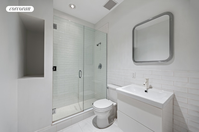 bathroom featuring toilet, vanity, tile walls, walk in shower, and tile patterned floors