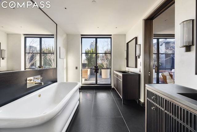 bathroom with vanity, a wealth of natural light, a washtub, and expansive windows