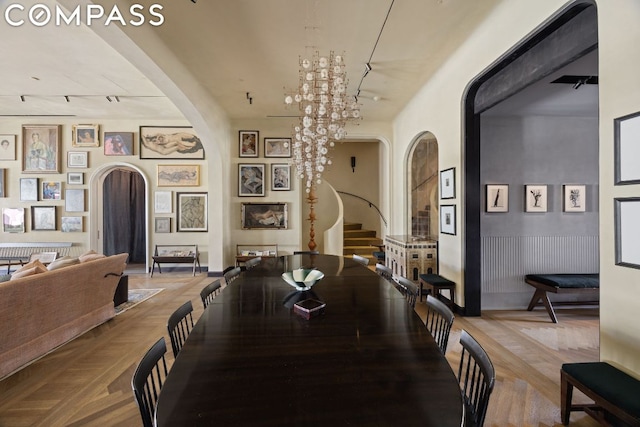 dining space featuring light parquet flooring, track lighting, and an inviting chandelier