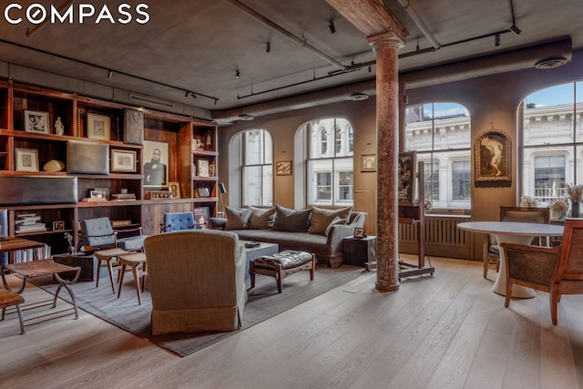 living room with rail lighting, light hardwood / wood-style flooring, and decorative columns