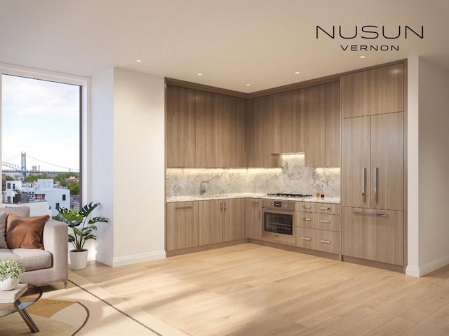 kitchen featuring backsplash, light hardwood / wood-style floors, sink, expansive windows, and stainless steel appliances