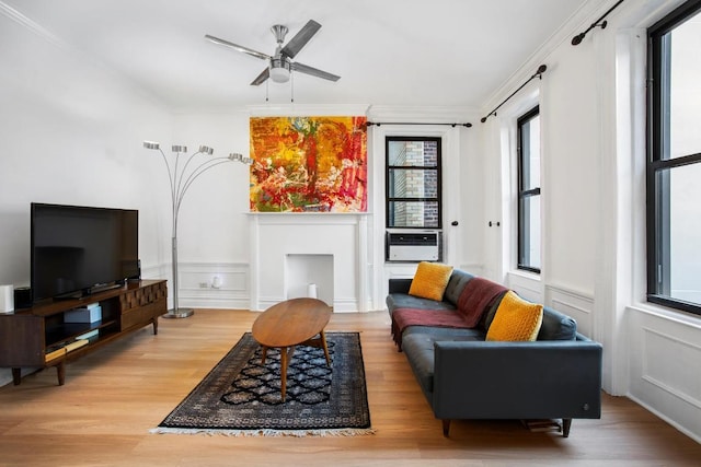 living room with light wood-type flooring, ceiling fan, and ornamental molding