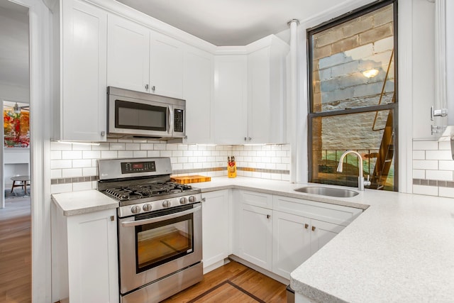 kitchen featuring light countertops, appliances with stainless steel finishes, backsplash, and a sink