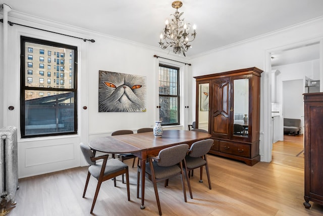 dining room featuring light wood-style floors, radiator heating unit, and crown molding