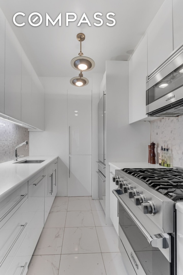 kitchen with marble finish floor, appliances with stainless steel finishes, white cabinetry, a sink, and modern cabinets