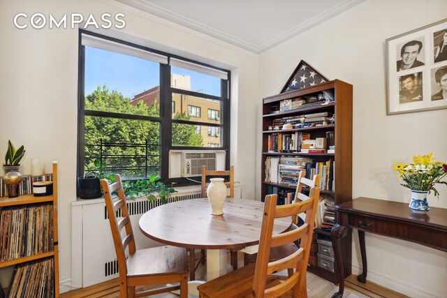 dining area with hardwood / wood-style flooring, ornamental molding, and cooling unit