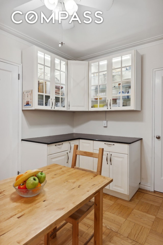 kitchen featuring dark countertops, glass insert cabinets, and white cabinets