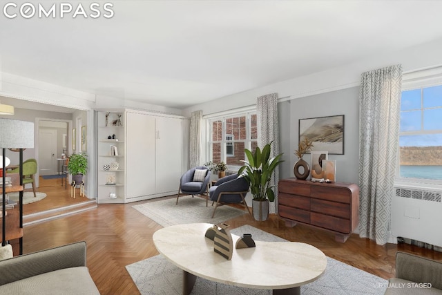 living room with radiator, a water view, and parquet flooring