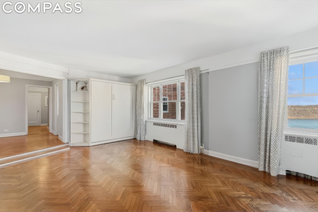 unfurnished bedroom featuring radiator and parquet flooring