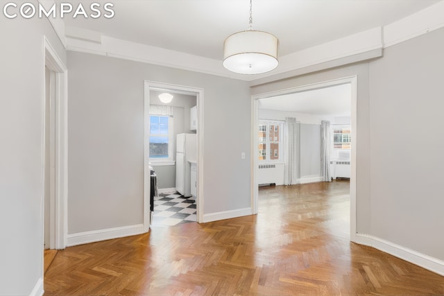 hallway featuring parquet flooring, radiator heating unit, and a healthy amount of sunlight