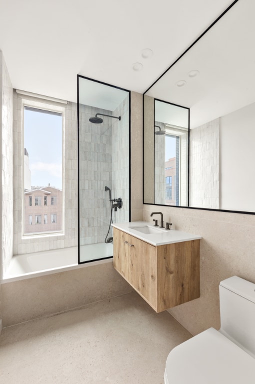 full bathroom featuring plenty of natural light, toilet, vanity, and tiled shower / bath