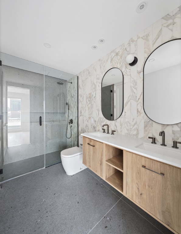 bathroom featuring toilet, tile walls, a shower with shower door, and vanity