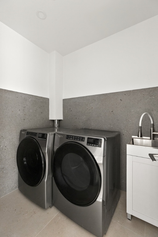 clothes washing area featuring cabinets, light tile patterned flooring, washing machine and clothes dryer, and sink