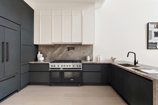 kitchen with tasteful backsplash, sink, high end appliances, light hardwood / wood-style flooring, and white cabinetry