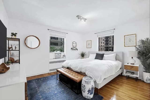 bedroom featuring cooling unit, dark hardwood / wood-style flooring, and radiator heating unit