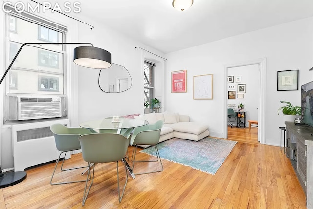 living room featuring cooling unit, radiator heating unit, and light wood-type flooring