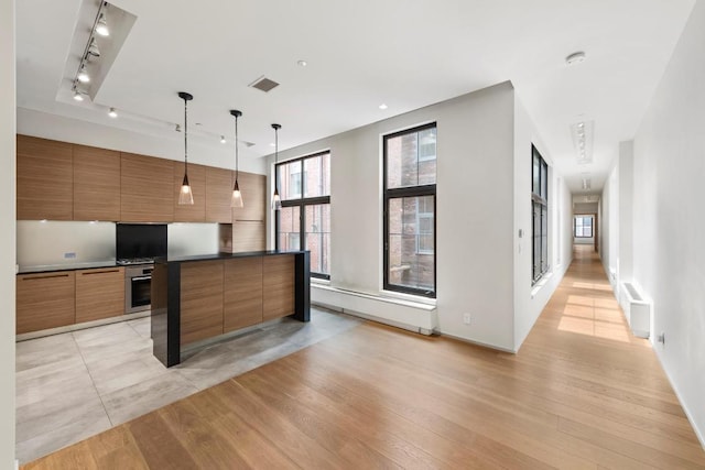 kitchen with stainless steel oven, a center island, light hardwood / wood-style floors, and pendant lighting