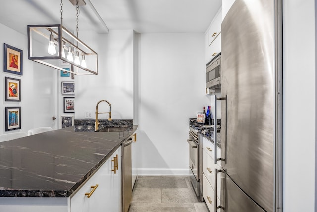 kitchen with white cabinetry, stainless steel appliances, dark stone counters, pendant lighting, and sink