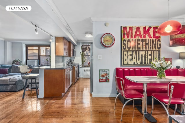 kitchen with kitchen peninsula, a kitchen bar, ornamental molding, and hardwood / wood-style flooring