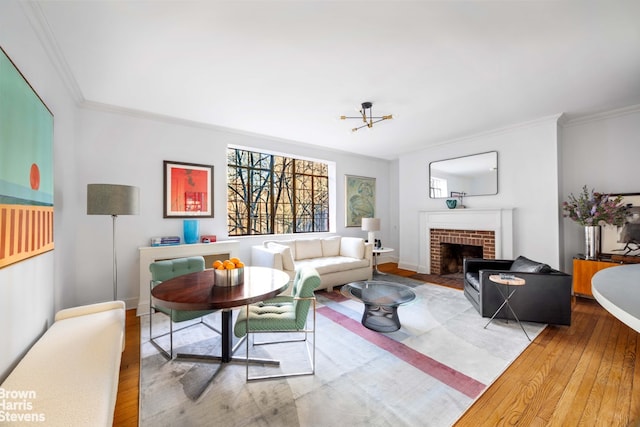 living room with wood-type flooring, a fireplace, crown molding, and a notable chandelier